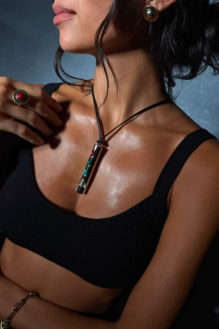 Deloris Red Circle Ring in textured brass with a red semi-precious stone, worn by a model in a black ribbed top.