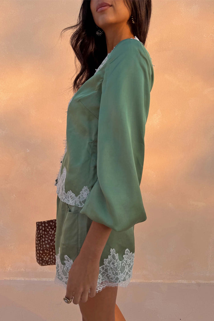 Green Lace Romi Top in soft green satin with white lace trim and voluminous long sleeves.