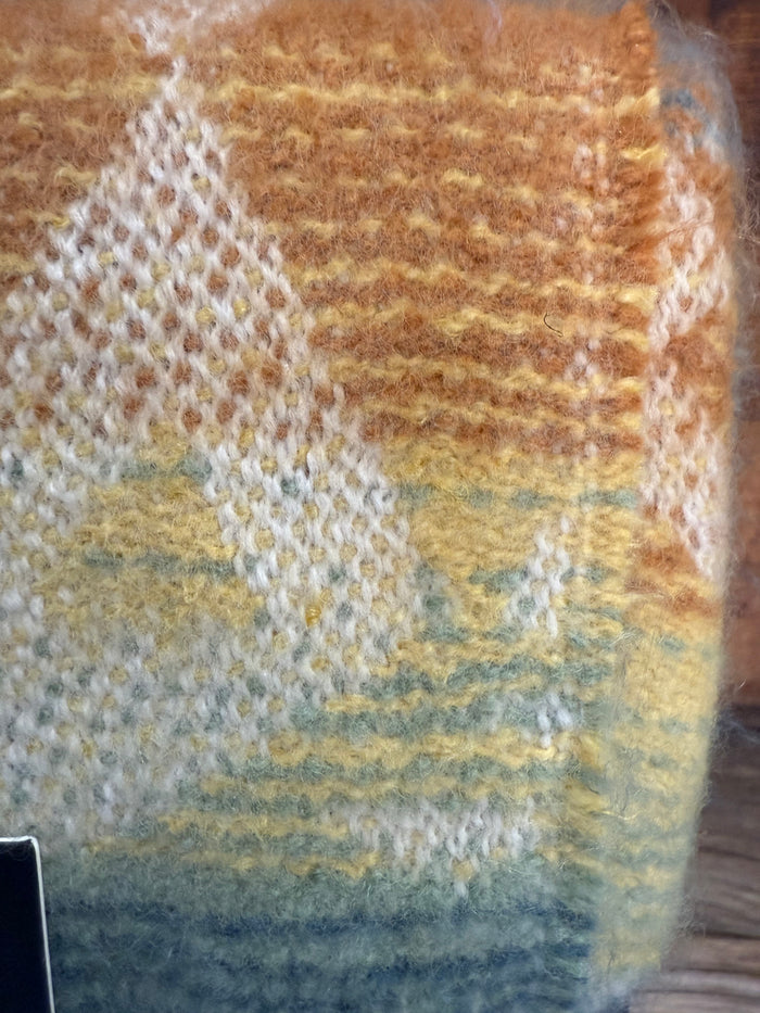 Jacquard throw blanket close-up with orange, yellow, and blue woven pattern.