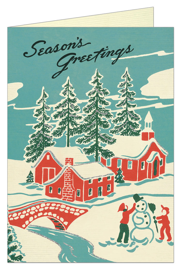 Front of card showing rural scene with children making a snowman and red home and church with trees in background.