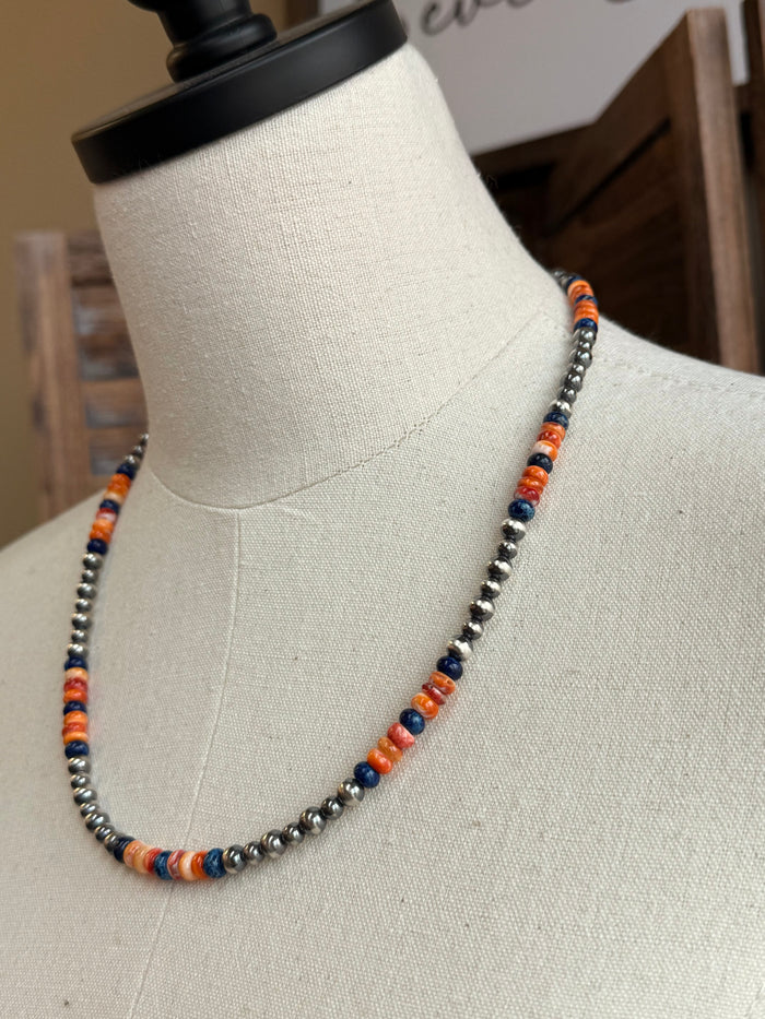 Close-up of multicolor spiny oyster and silver-toned beaded necklace on mannequin