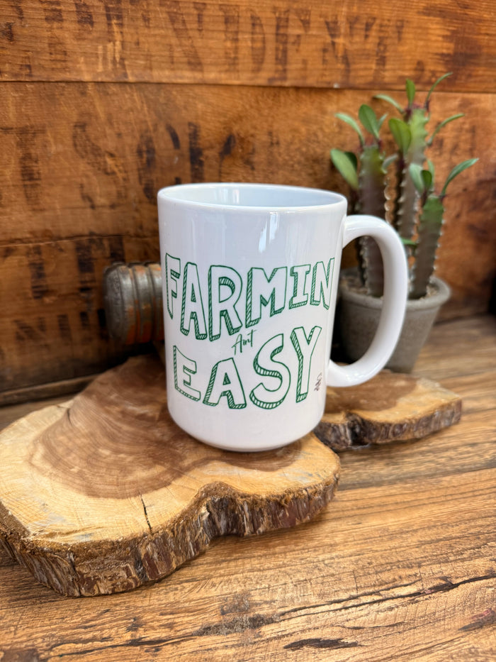 White ceramic mug with green 'FARMIN' AIN'T EASY' text and side handle