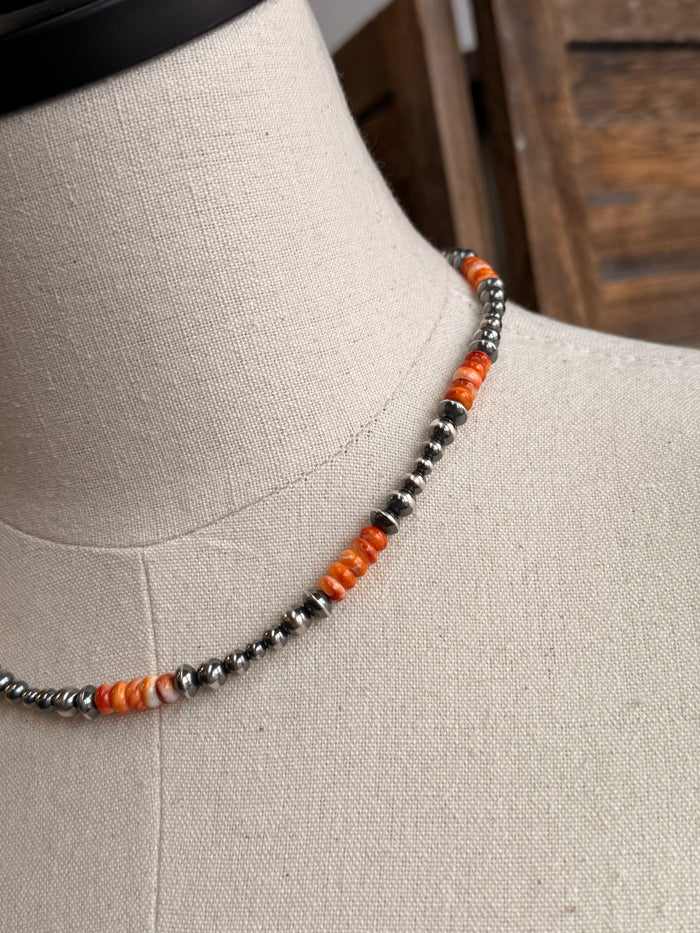Orange spiny bead strand with silver-tone bead accents, close-up