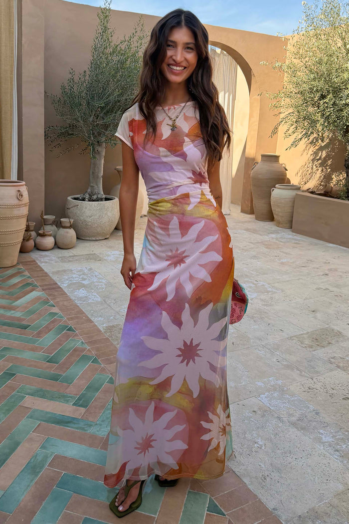 Abstract Soleil Luna Mesh Dress featuring iconic sun motifs on a multicoloured mesh base in a sunny outdoor setting.