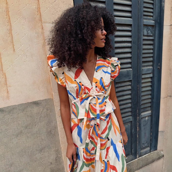 Banana Kerri Top with a colourful banana print, ruffle sleeves and a tie-front waist in cream cotton.