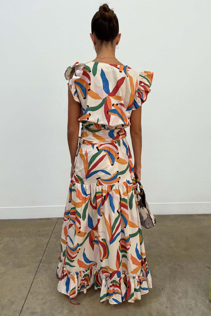 Banana Saige Skirt in a multicolour banana print with a tiered frill hem, styled as a cotton co-ord from behind.