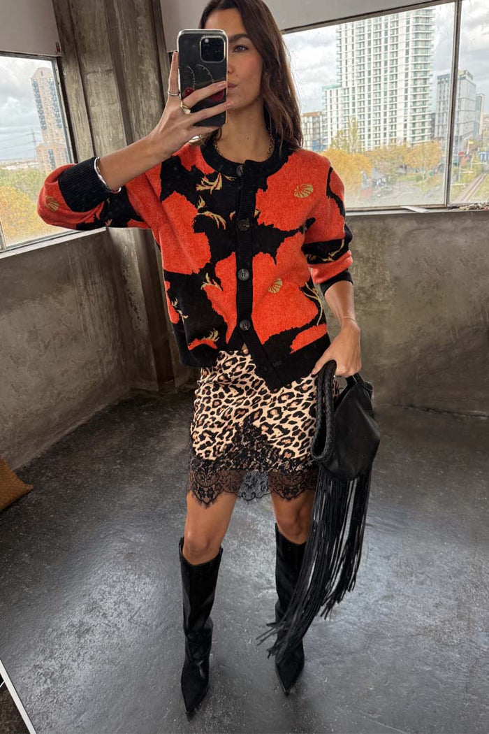 Black Poppy Cardigan with a red floral print, styled with a leopard print lace skirt and black fringed bag.