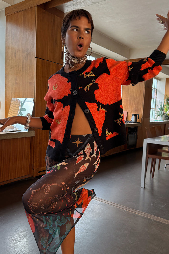 Soft-touch Black Poppy Cardigan with a red poppy print and wide sleeves, styled over a matching mesh dress.