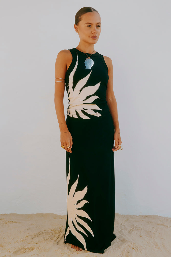 Black Sol Tank Top with a hand-painted sun print, styled with a matching maxi skirt in a beach setting.