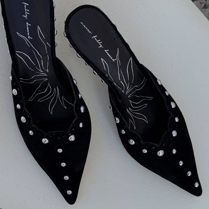Black suede pointed-toe mules with silver studs and scalloped edges, featuring NFD line art on the inner sole.