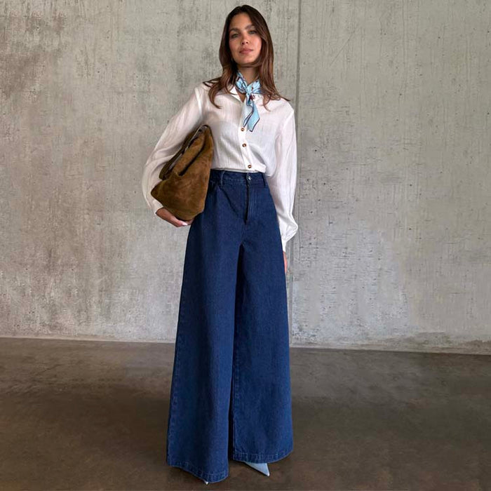 Blue Denim Pallazzo Jan Jeans in a wide-leg style, paired with a white shirt, patterned neck scarf and brown bag.