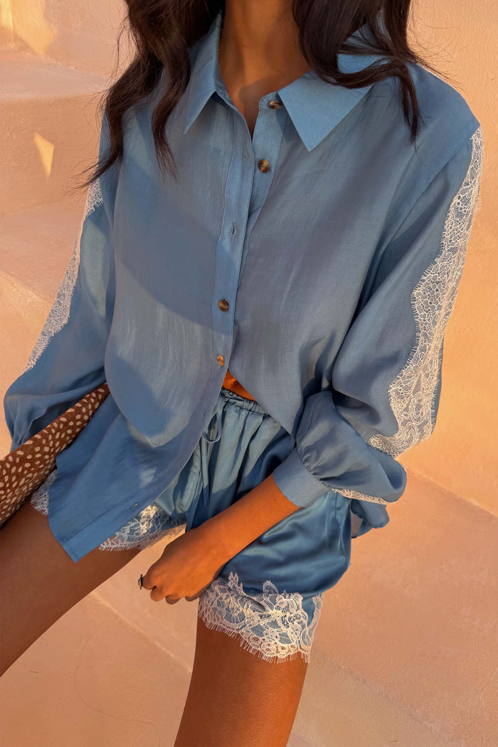 Blue Lace Maeva Shorts in washed blue satin with white lace trim, styled with a matching long-sleeved shirt.