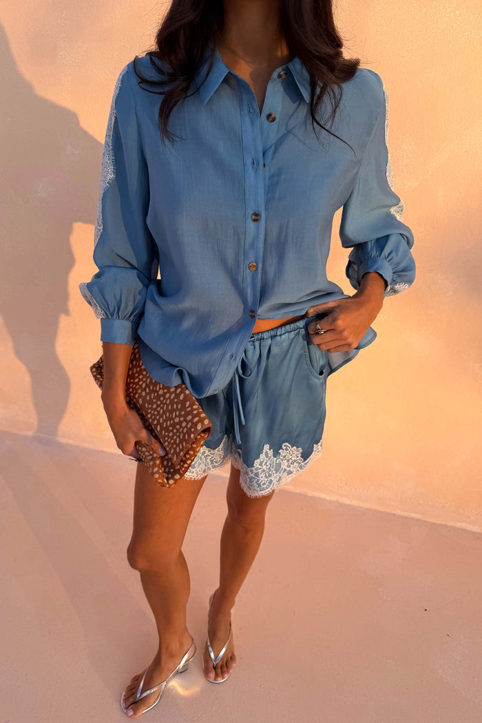 Blue Lace Maeva Shorts with white lace edging, styled with a matching shirt and leopard print clutch on a model.