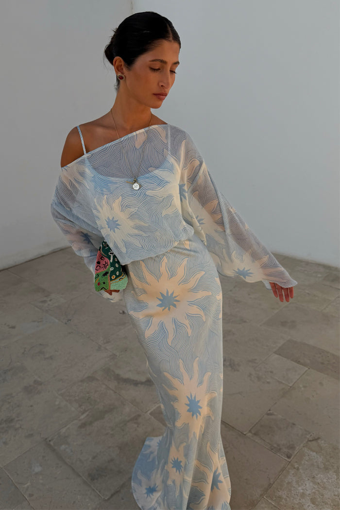 Blue Soleil Anais Dress with a Mediterranean sun print, sheer off-the-shoulder top and satin-esque skirt.