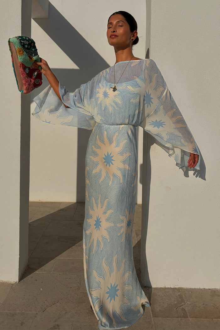 Blue Soleil Anais Dress with Mediterranean sun motifs, a sheer draped top and a flowing satin-esque maxi skirt.