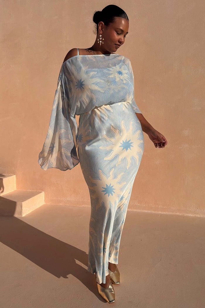 Blue Soleil Anais Dress with sun motifs, off-the-shoulder top and a bias cut maxi skirt on a curve model.