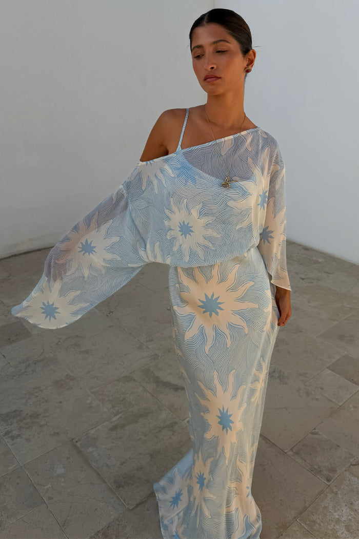Blue Soleil Anais Dress featuring a sheer off-the-shoulder draped top and sun motif print on a bias-cut skirt.