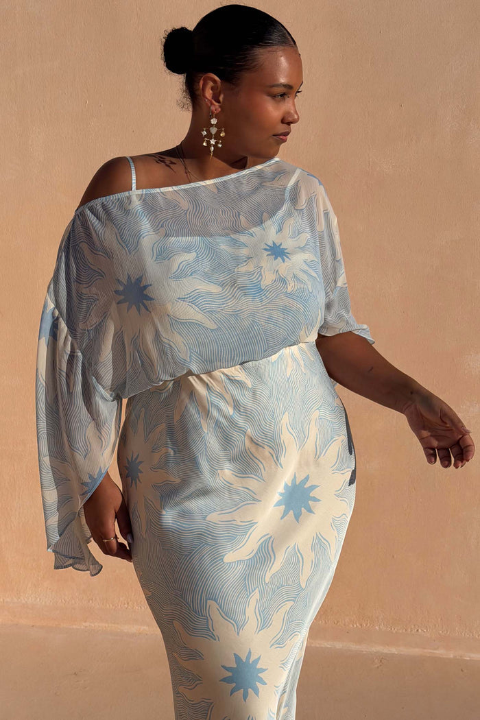 Blue Soleil Anais Dress featuring a sheer off-the-shoulder top and Mediterranean sun motif skirt in inclusive sizing.