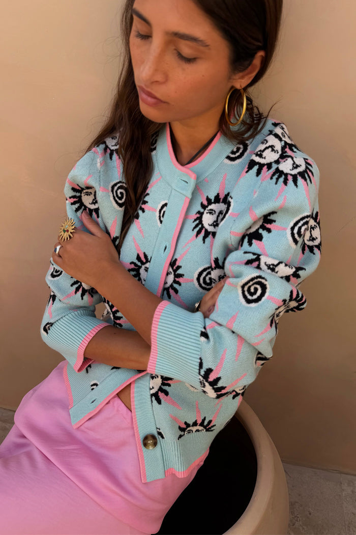 Blue Sun Hollie Cardigan in baby blue knit with a pink sun face print and contrasting pink ribbed trims.