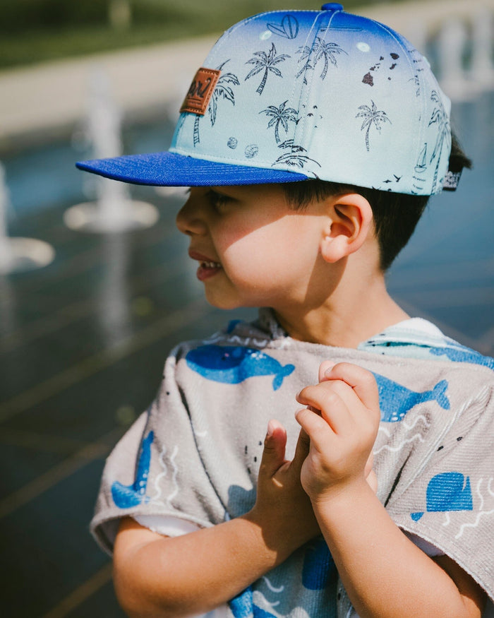 Deux par Deux boys' blue beach print flat-brim cap – worn by a boy outdoors
