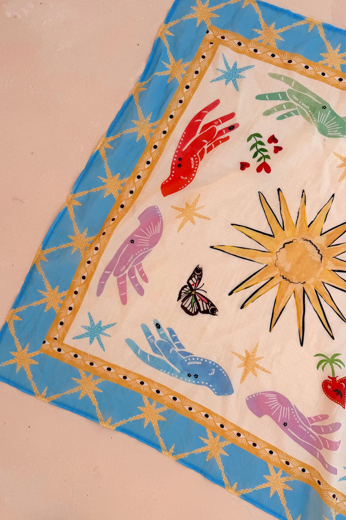 Celestial Bandana featuring a blue border with hand-painted sun, palm, eye, and mystical hand motifs.