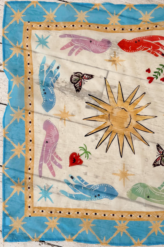 Celestial multi-wear bandana with a blue border and in-house hand-painted sun and mystical hand motifs.