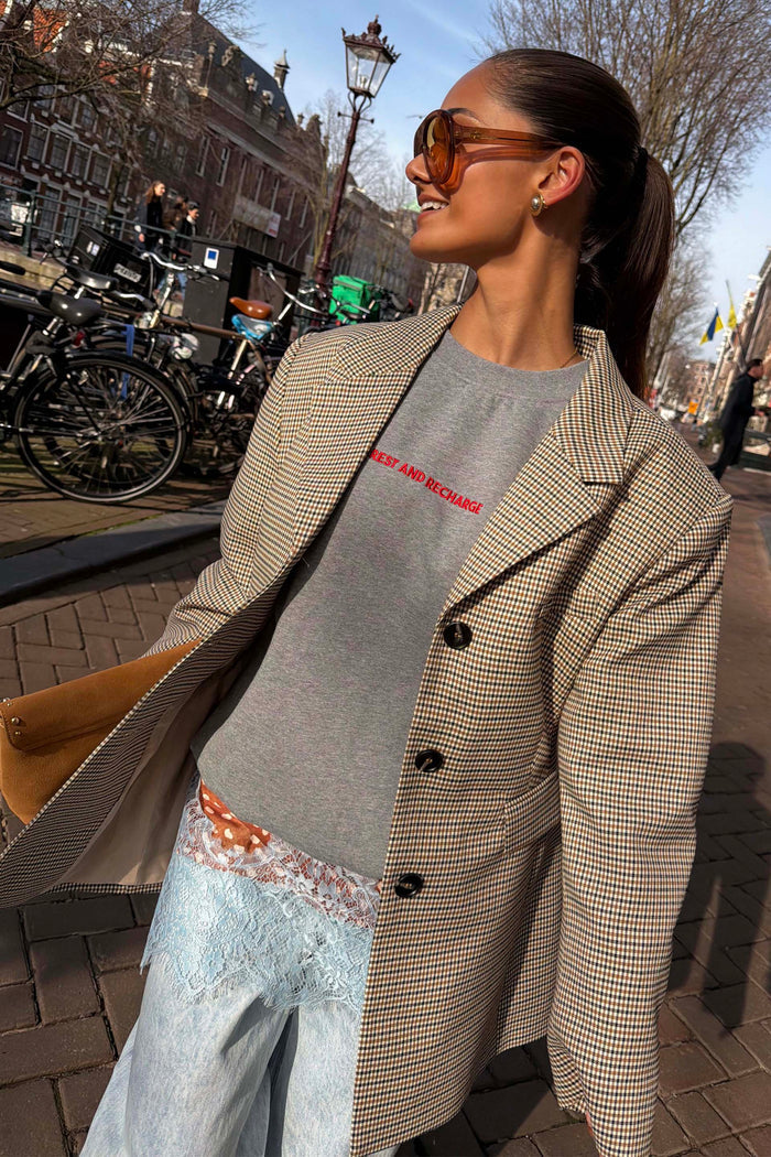 Grey tailored Check Blazer with button detailing and structured darts, styled over a grey slogan sweatshirt in an outdoor setting.