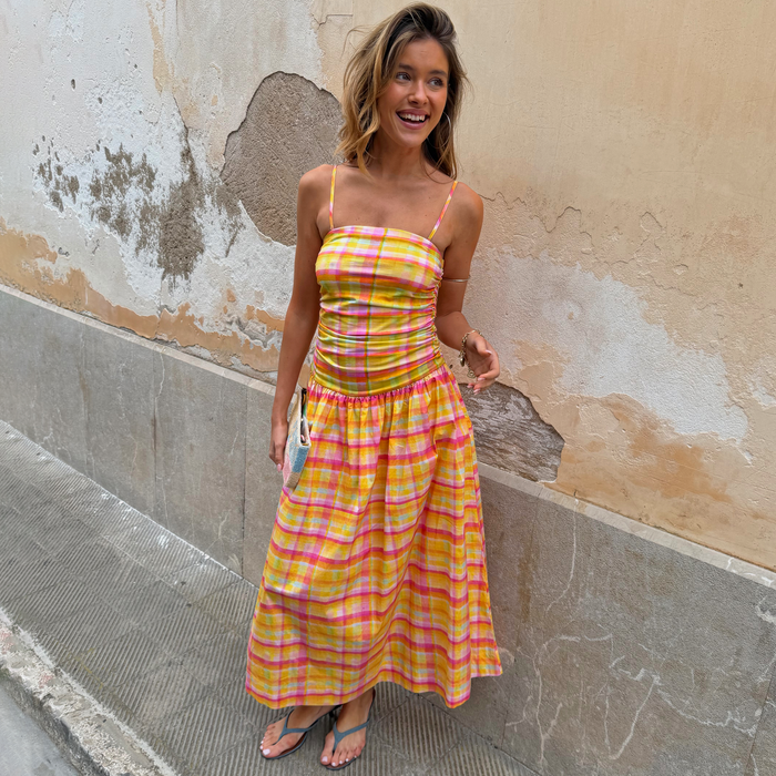 Check Lola Mid-axi Dress in yellow, pink and orange with a ruched bodice and cotton skirt, styled for vacation.