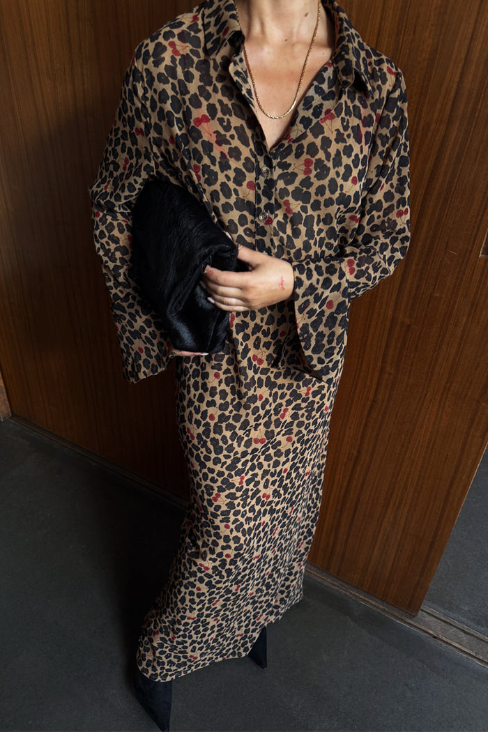Cherry Leopard Mia Dress featuring a leopard print with red cherry details, button up front and long sleeves.