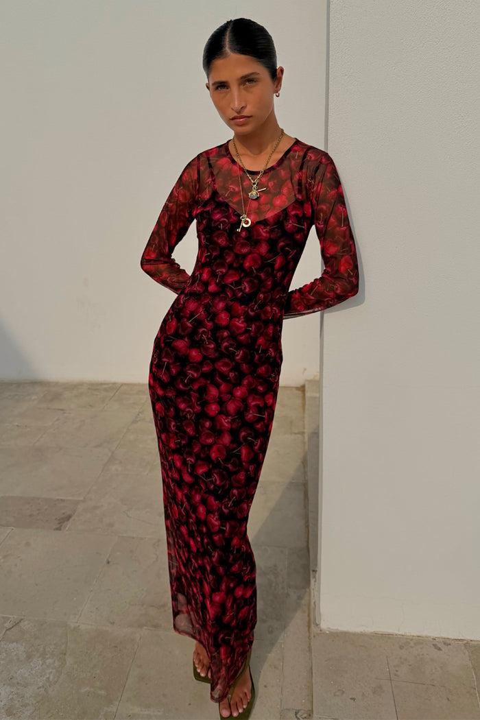 Cherry Mesh Soho Dress with a red digital cherry print, sheer long sleeves and a maxi length, worn by a model.