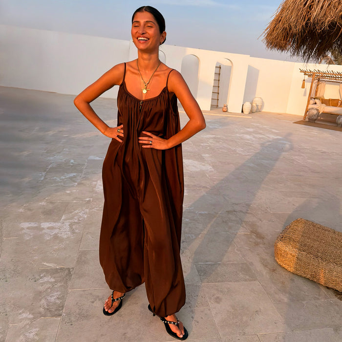 NFD Chocolate Balloon Jumpsuit with a loose draped silhouette and gathered neckline, styled in a vacation setting.