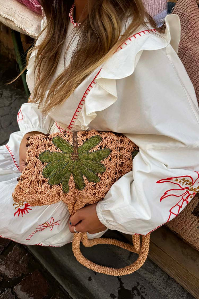 Cream Pollenca Mini Dress in cotton with red embroidery and ruffles, styled with a woven palm tree bag.