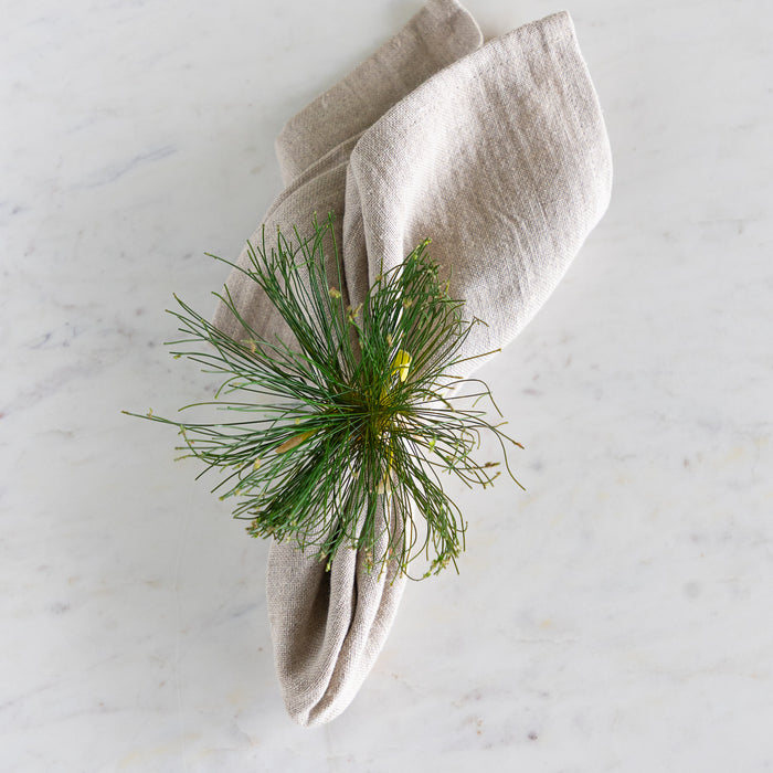 Cypress Bloom Napkin Ring with a beige napkin on a marble table.