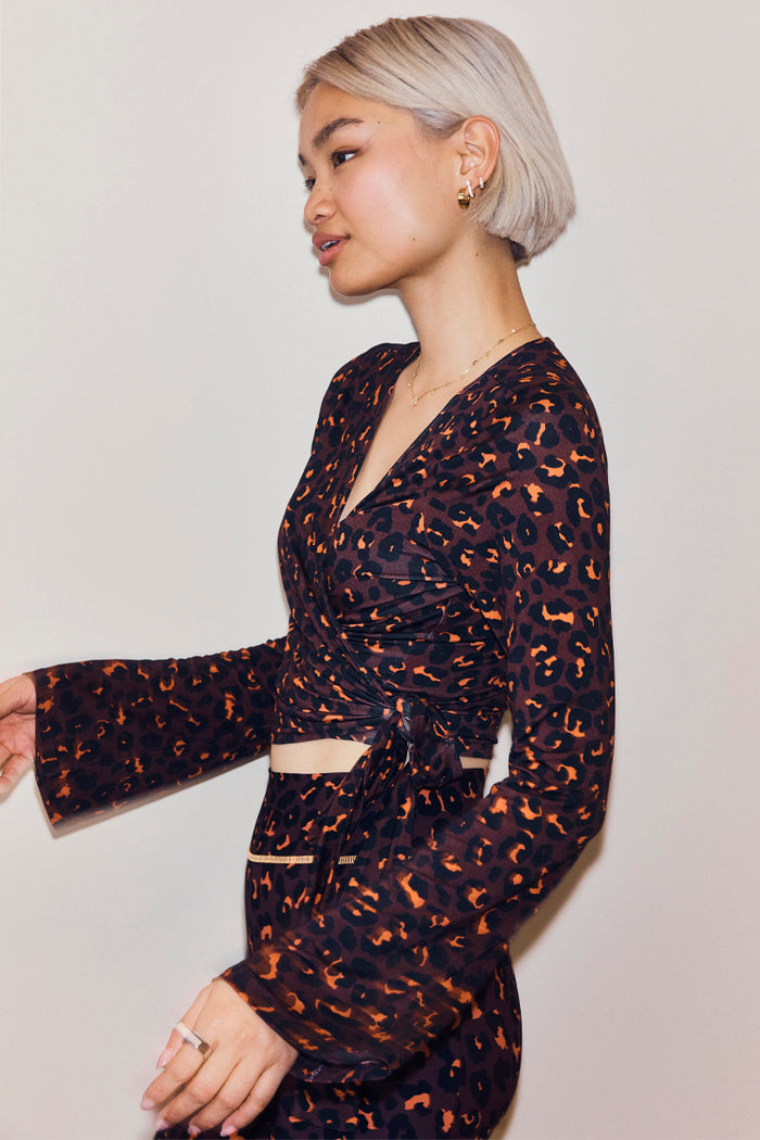 Dark Leopard Ballet Wrap top with flared sleeves and a wrap tie closure in an iconic leopard print with orange accents.