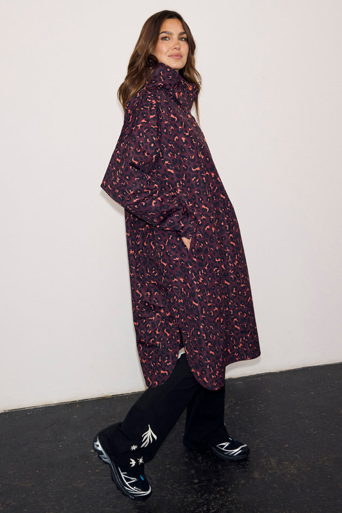 Dark Leopard Rain Mac in a waterproof fabric with an iconic animal print, relaxed fit and side pockets on a model.