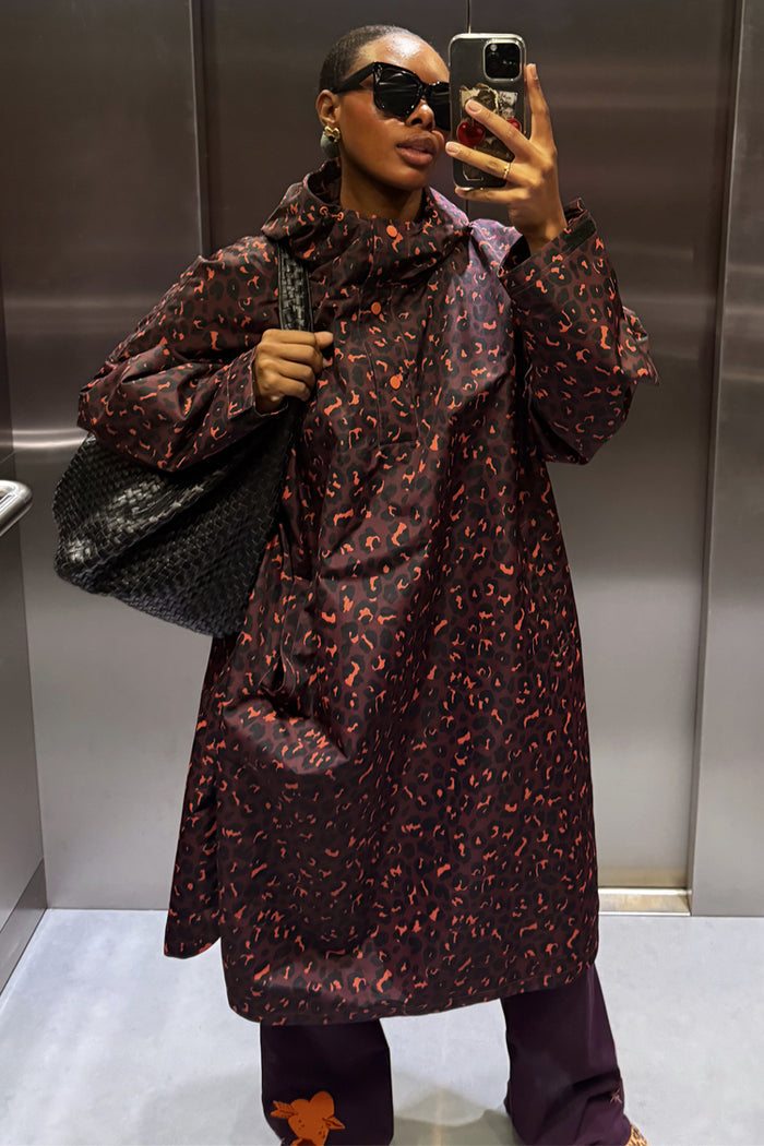 Dark Leopard Rain Mac with a hood in a mirror selfie, featuring a large black woven bag and dark purple trousers.