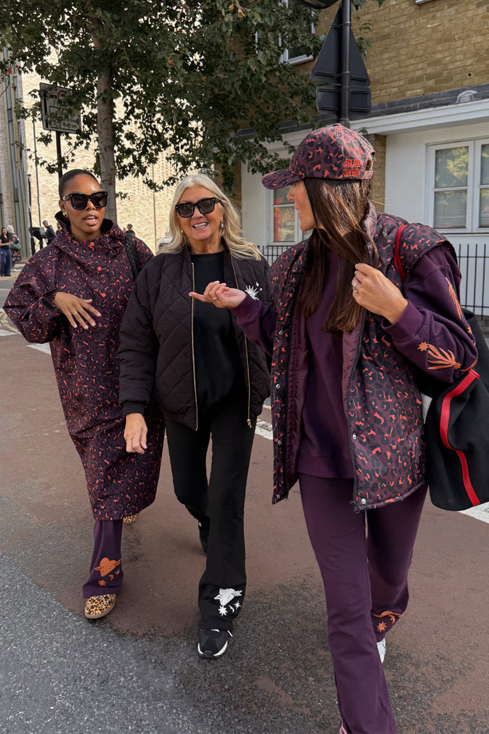 Dark Leopard Rain Mac in a waterproof recycled fabric, styled on a woman walking with her community in London.