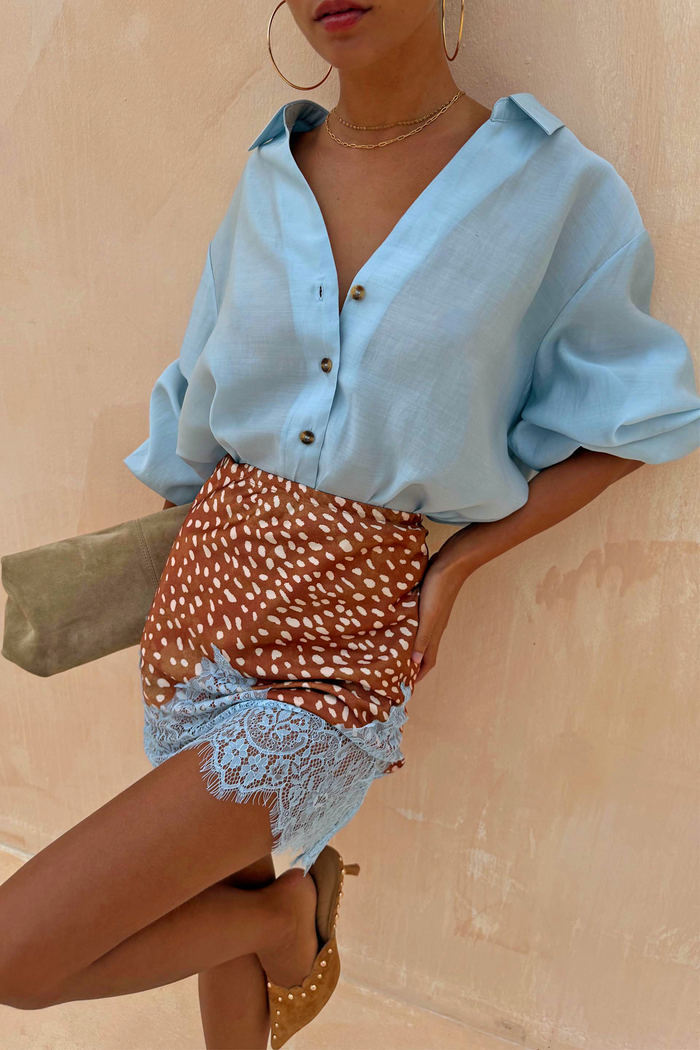 Fawn Mini Maeva Skirt with a brown animal print and blue lace hem, styled with a light blue shirt.