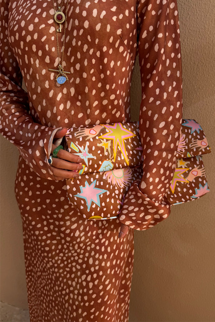 Fawn Soho Dress in brown satin with a cream spotted print, styled with a colourful star print clutch.
