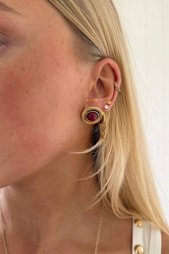 Deloris Red Circle Earrings in textured brushed brass with a red stone, worn by a blonde model for a vintage look.