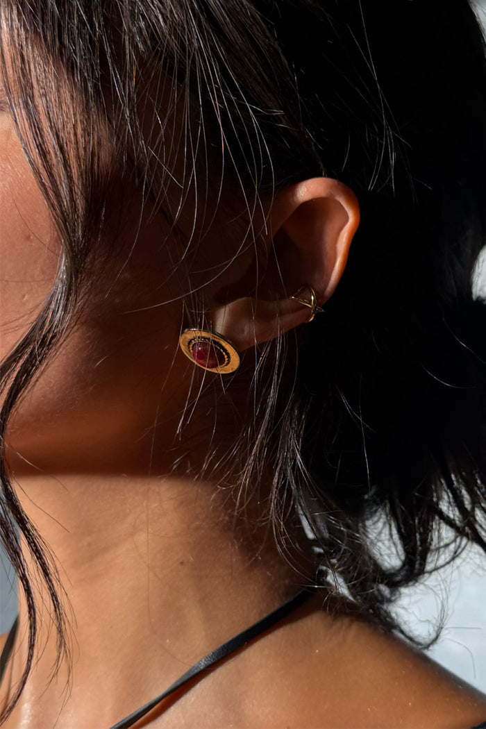 Deloris Red Circle Earrings in textured brushed brass with a red semi-precious stone, shown on a model.