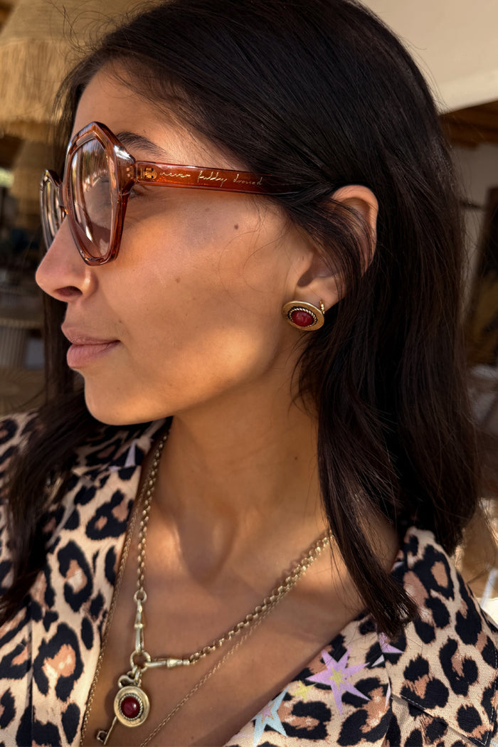 Deloris Red Circle Earrings in textured brushed brass with a red stone, styled with a leopard print top.