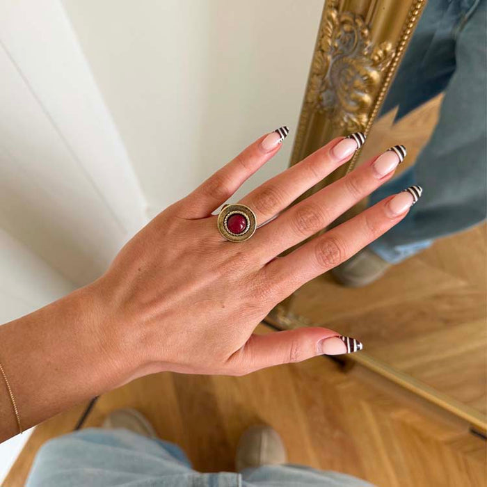 Deloris Red Circle Ring designed in London, featuring textured brass and a round red stone, worn on a hand.