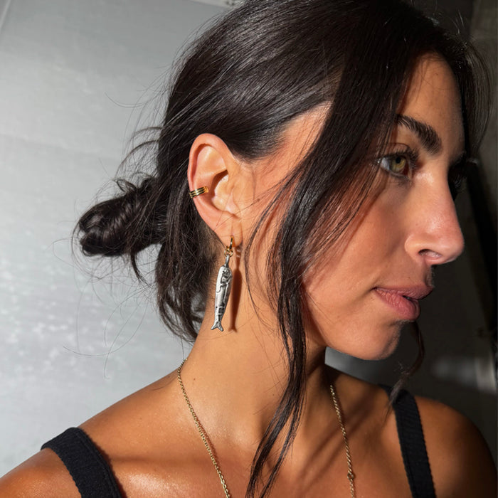 Deloris Sardine Earrings in mixed-metal brass, featuring a silver fish pendant hanging from a gold hoop.