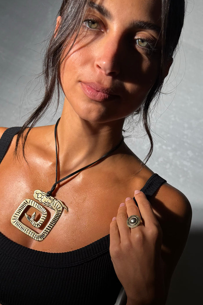 Deloris Silver Circle Ring in brushed metal with textured detail, worn on a model's hand with a statement necklace.