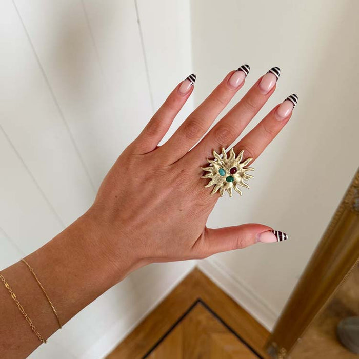 Deloris Sun Ring in brass with semi-precious stones and an iconic sun motif design worn on a hand.