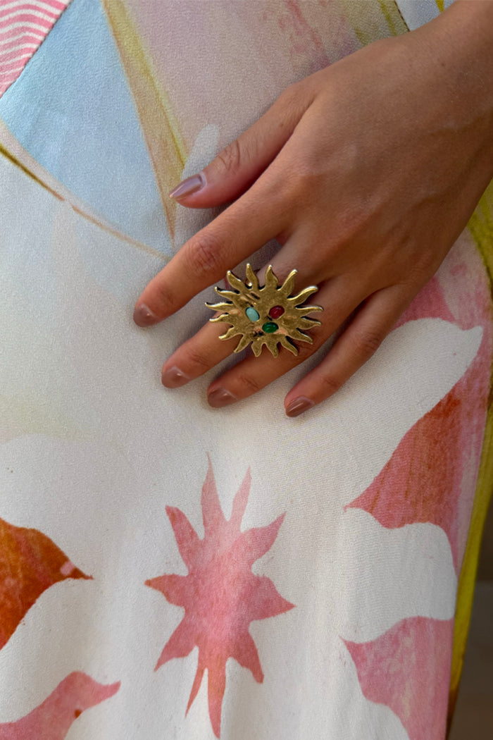 Deloris Sun Ring in brass featuring an iconic sun motif and semi-precious stones, worn on a hand.