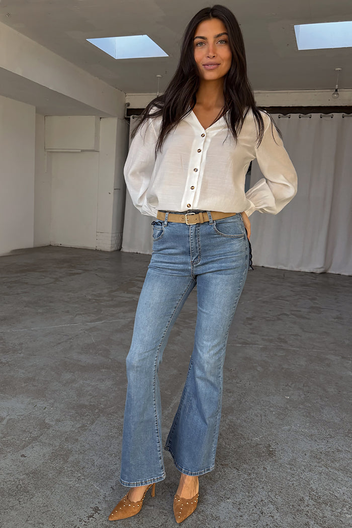 Blue Denim Flare Scallop Jean with a 70s flared silhouette, styled with a white button-down blouse.
