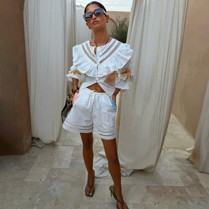 Dreamer Willa Top in white cotton with iconic sun motifs, ruffle cutout neckline and flared cuffs, styled as a co-ord.