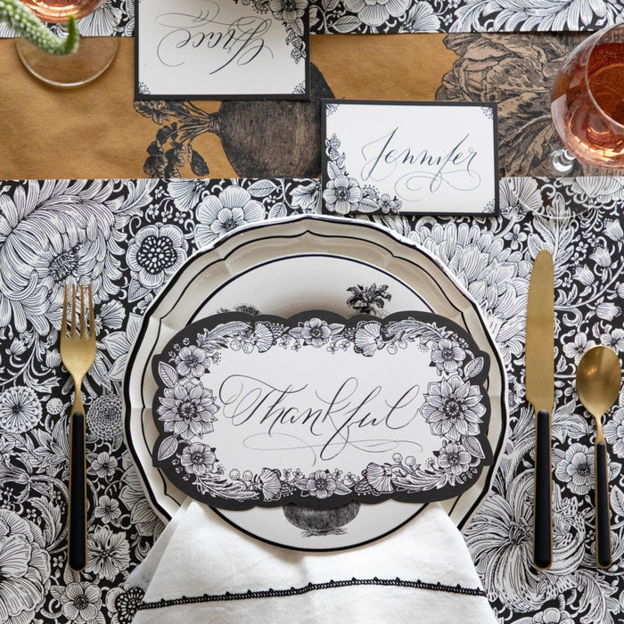 An elegant place setting featuring an Ebony Harvest Blooms Table Card with "Thankful" written on it in lovely script resting on the plate.